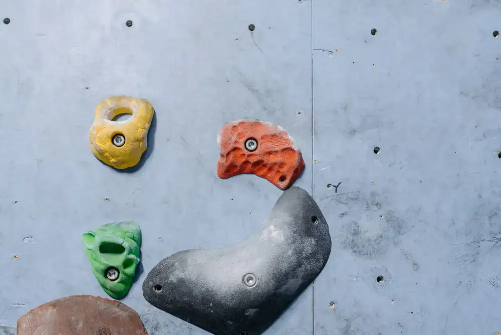 Close up view of colourful climbing holds mounted on a textured wall